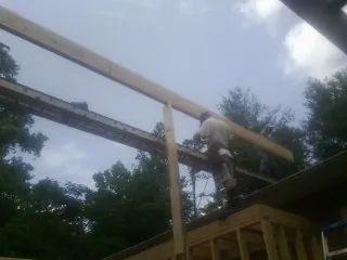 Carpenter setting a ridge beam over a new addition frame — Ice Dam Removal by Roofing Brothers in Goffstown