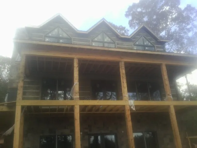 Dormers and porch framing on a large log home under construction — Roof Coating work by our crew in Goffstown