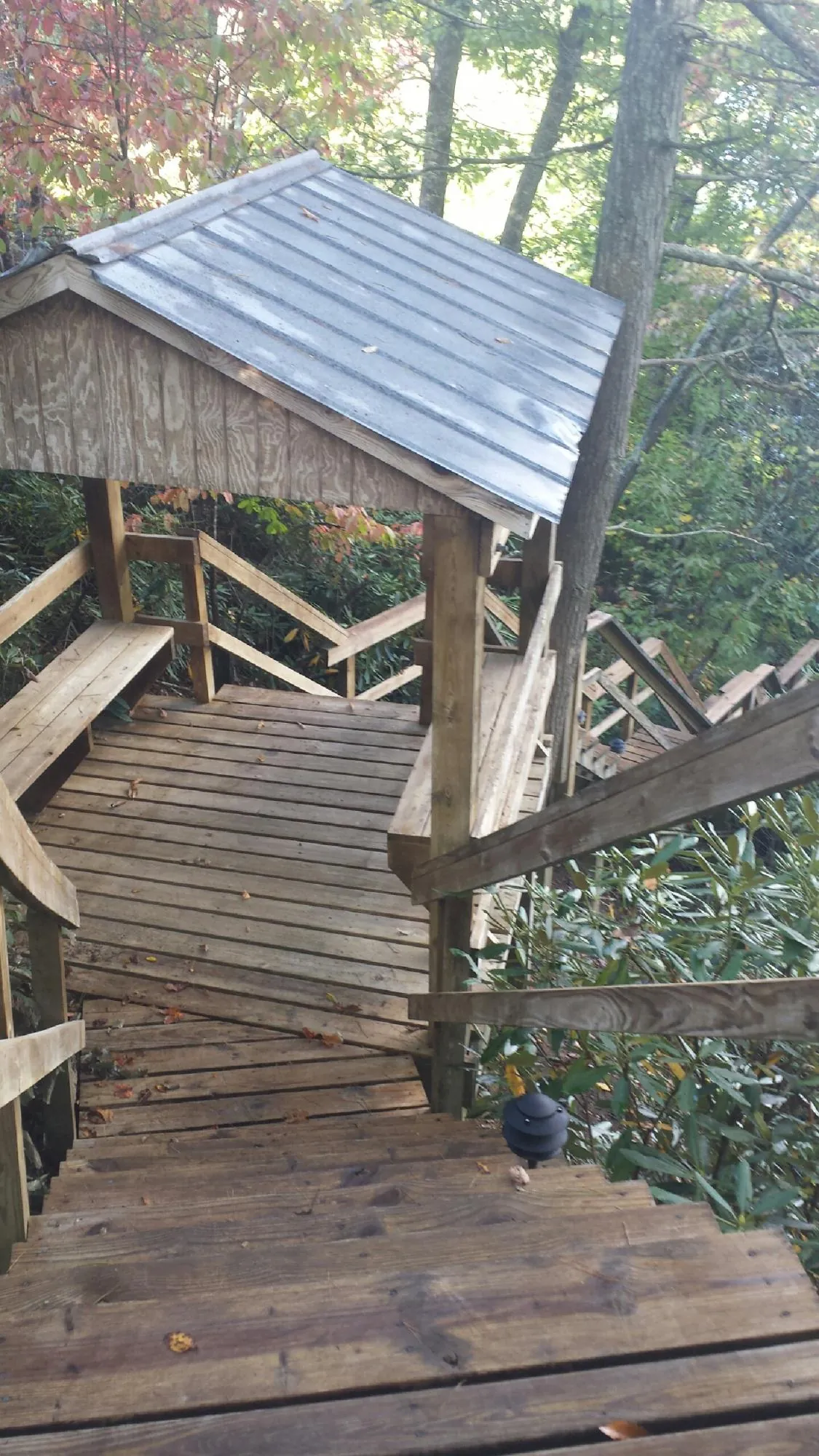 Metal roofed shelter over wooden steps on a wooded walkway — Skylight Repair & Installation work by our crew in Goffstown