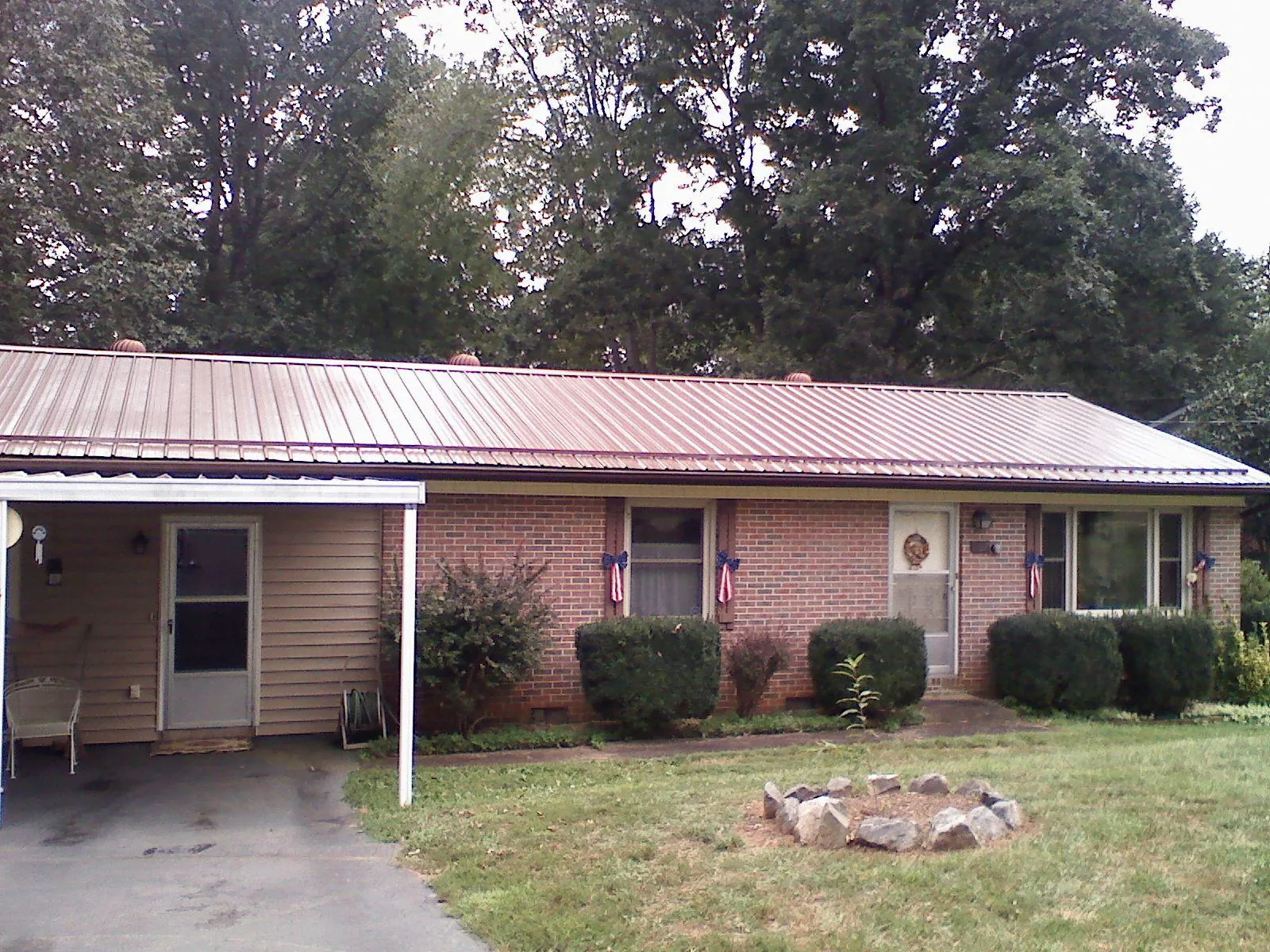 Bronze metal roof and carport on a brick ranch home — Roof Repair work by our crew in Goffstown