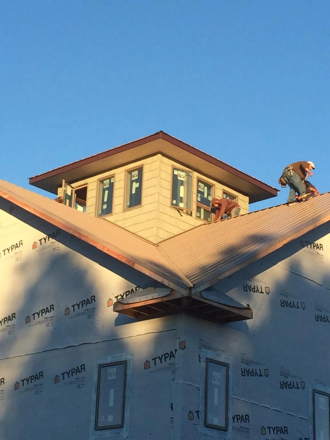 Roofers working around a rooftop cupola on a new metal roof at sunset — Roof Waterproofing in Goffstown by Roofing Brothers